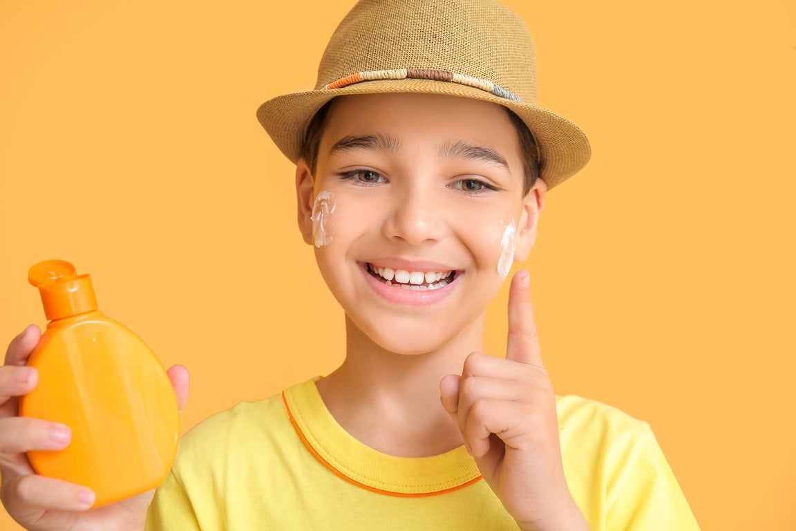 Boy with Sun Protection Cream on Yellow Background